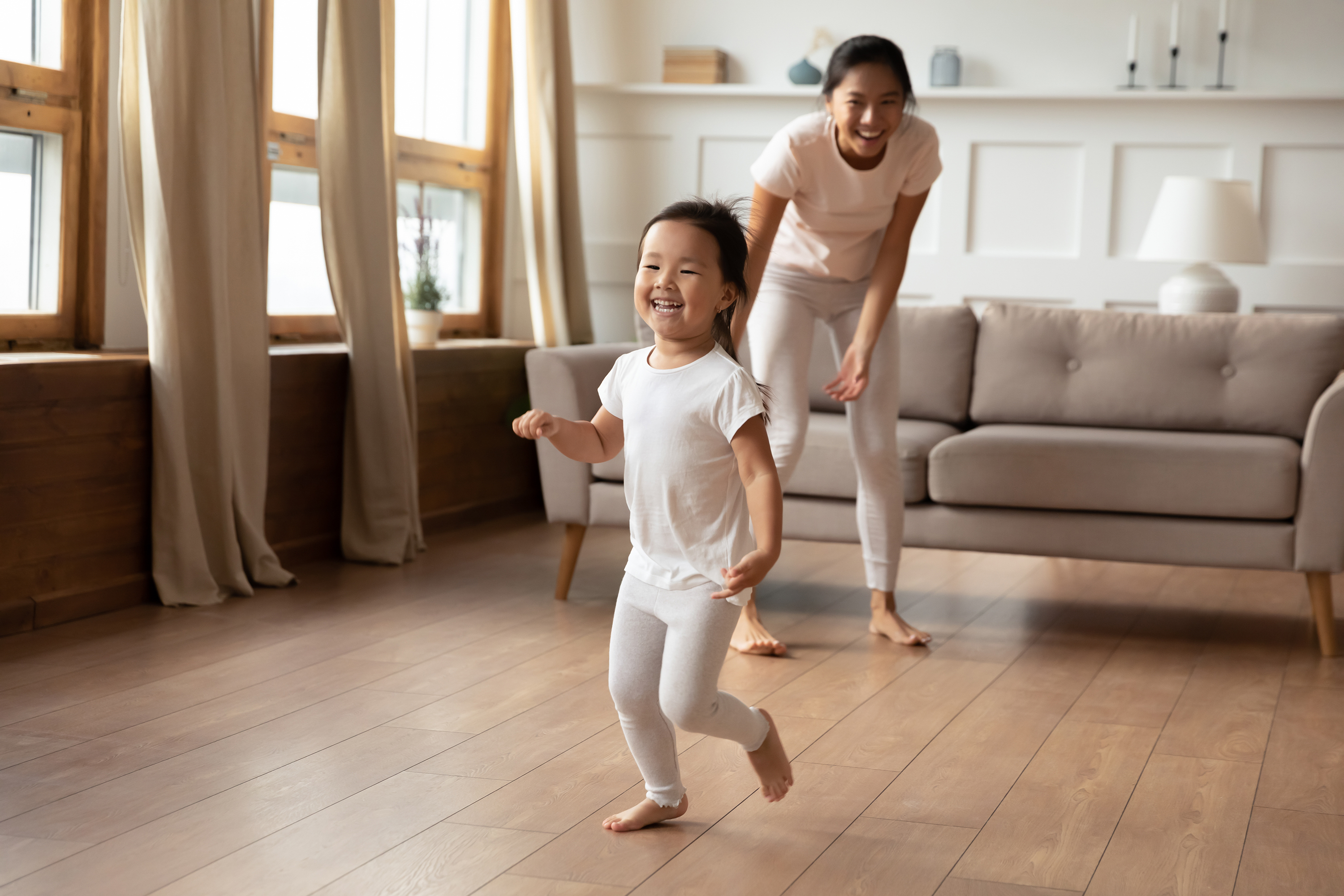 A caregiver and toddler playing together in a bright, warm living room